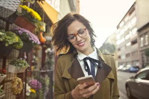 Eine Frau sucht unterwegs in Ihrem Smartphone ein lokales Unternehmen: SEO für lokale Unternehmen zahlt sich aus.
